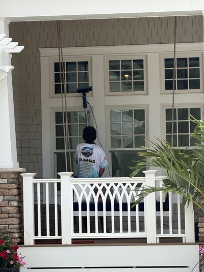 A Loukides Power Washing technician cleaning windows with a water-fed pole
