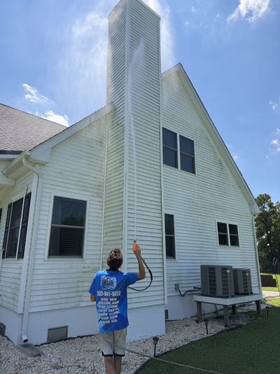 A Loukides Power Washing technician soft washing a chimney, mildew visibly lifting