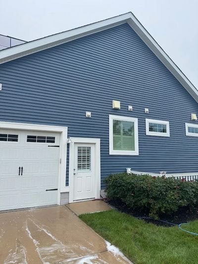 Soft washing a vinyl-sided home and rinsing the driveway